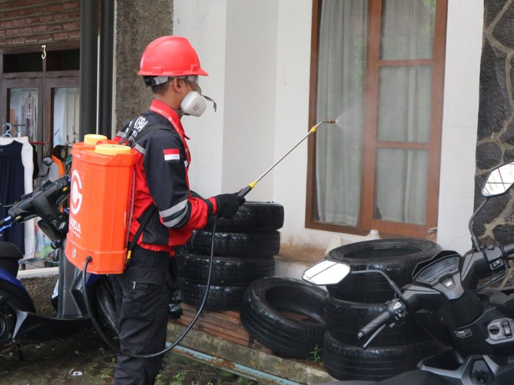 services-04 A worker in safety gear sprays disinfectant outside a building, ensuring cleanliness.