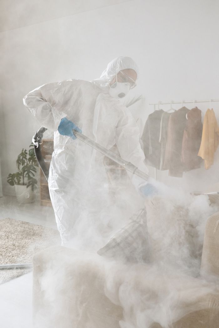 who-we-are Person in protective suit fogging indoors, enhancing cleanliness.
