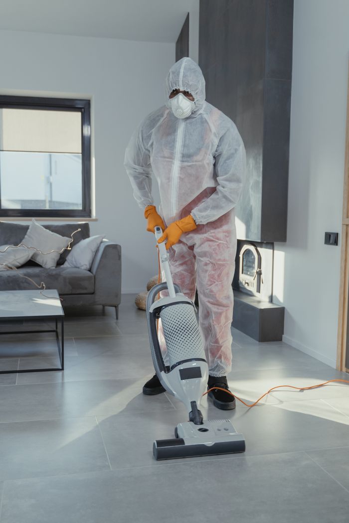 why-choose-us Cleaner wearing PPE with a vacuum cleaner maintaining hygiene in a modern indoor setting.